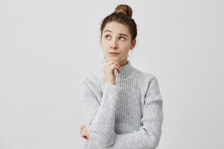 young woman with dark hair holding her chin looking sideways attractive girl having meaningful gaze side thinking about her future wistfully life goals concept 1024x683 1