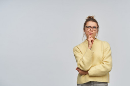 portrait thinking girl with blond hair gathered bun wearing yellow sweater glasses touching her chin thoughtfully watching left copy space isolated white wall 1024x683 1