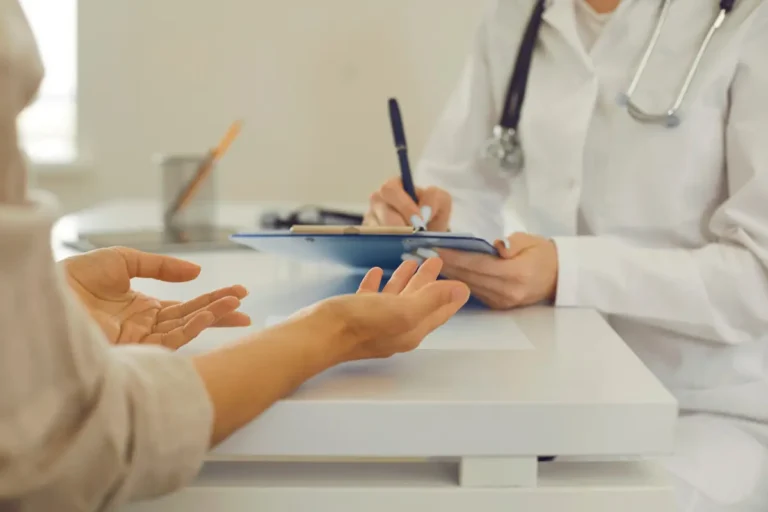 doctor taking notes while patient discusses symptoms during a medical consultation