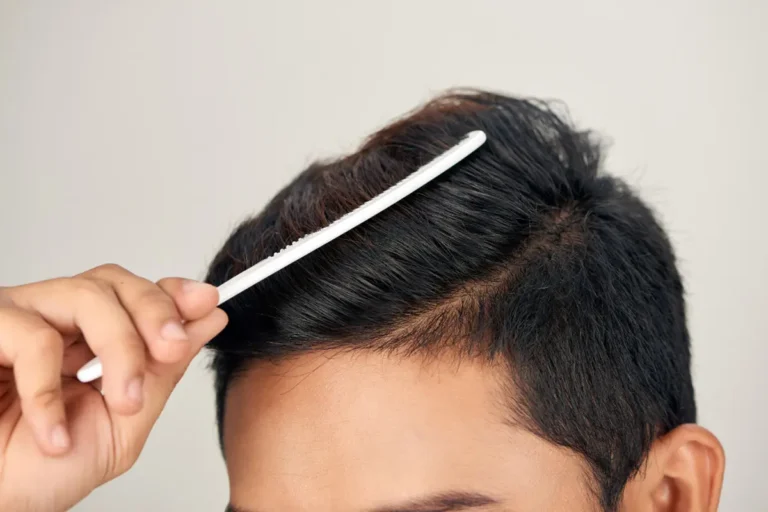 close-up of a man combing his thick dark hair with a white comb
